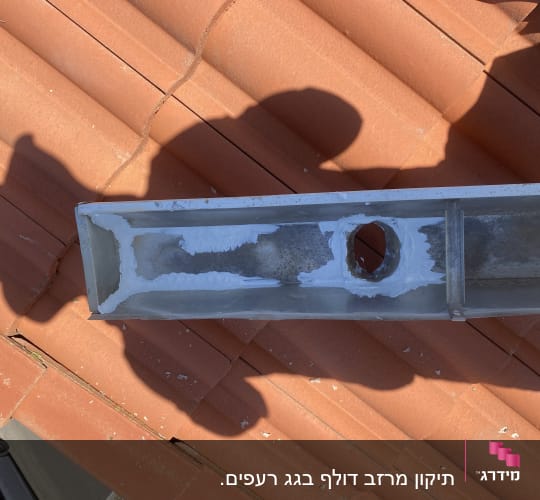 תעלת מתכת עם איטום לבן על גג רעפים אדום